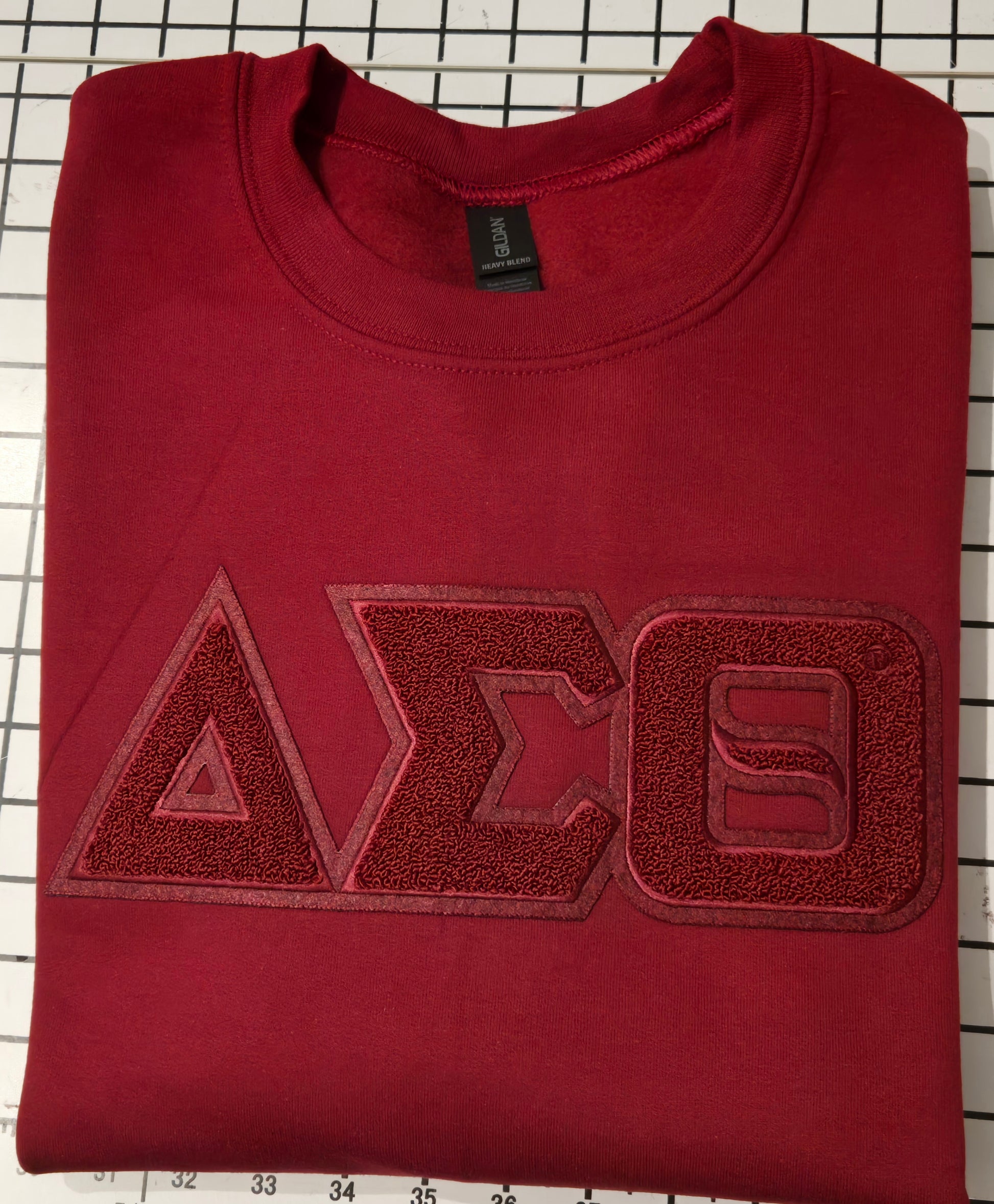 Folded red sweatshirt with a logo on a grid background