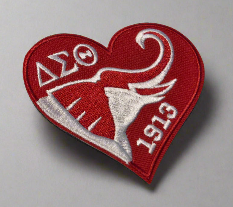 Red heart-shaped patch with white embroidery on a beige background