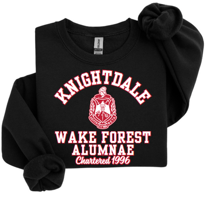 A collection of unisex sweatshirts in black, white, and red colors, featuring the text 'Knightdale Wake Forest Alumnae' and the logo of Delta Sigma Theta Sorority, Inc.